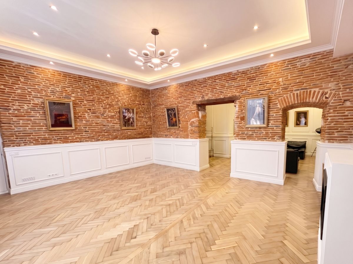 Grand salon rénové à Toulouse avec parquet en point de Hongrie, murs de brique et soubassements moulurés