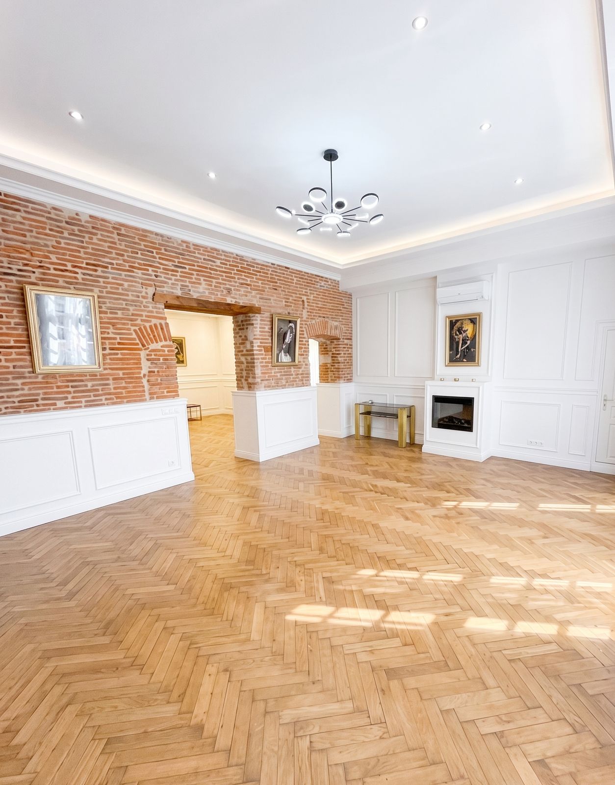 Salon rénové d'un hôtel particulier : mur de brique toulousaine, boiseries blanches, parquet en point de Hongrie, plafond lumineux